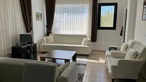 A living room with a sofa, armchairs, a coffee table, and a TV.