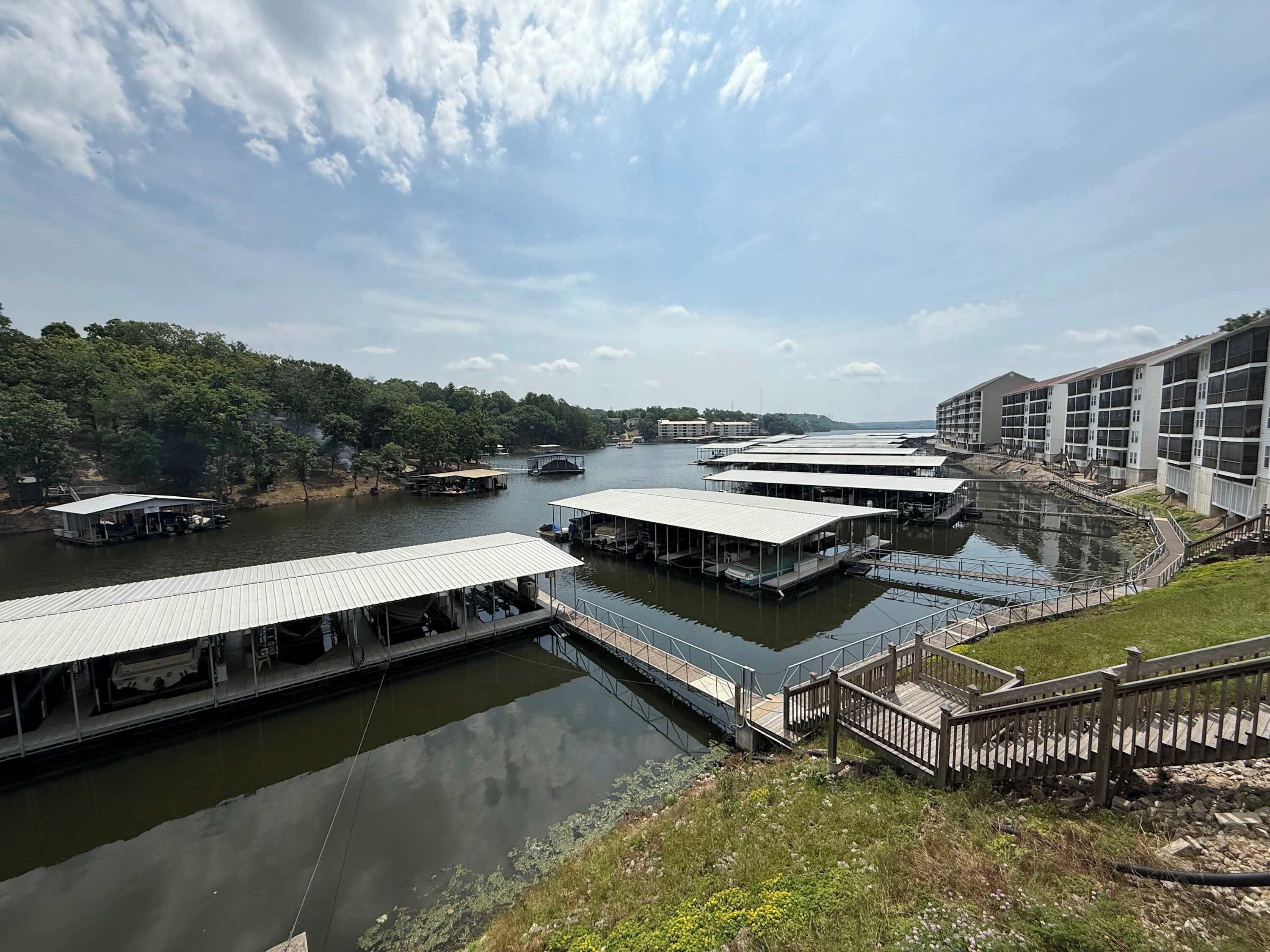 A riverside hotel with multiple docked boats, a pedestrian bridge, and a building with large windows.