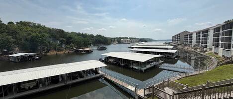 A riverside hotel with multiple docked boats, a pedestrian bridge, and a building with large windows.