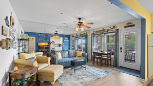 Un salón amplio con una decoración azul y amarilla, que incluye un sofá, un sillón y una mesa de comedor.