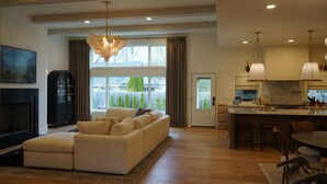 Ein geräumiges Wohnzimmer mit großem Sofa, Kamin und Essbereich, im Hintergrund eine Küche.