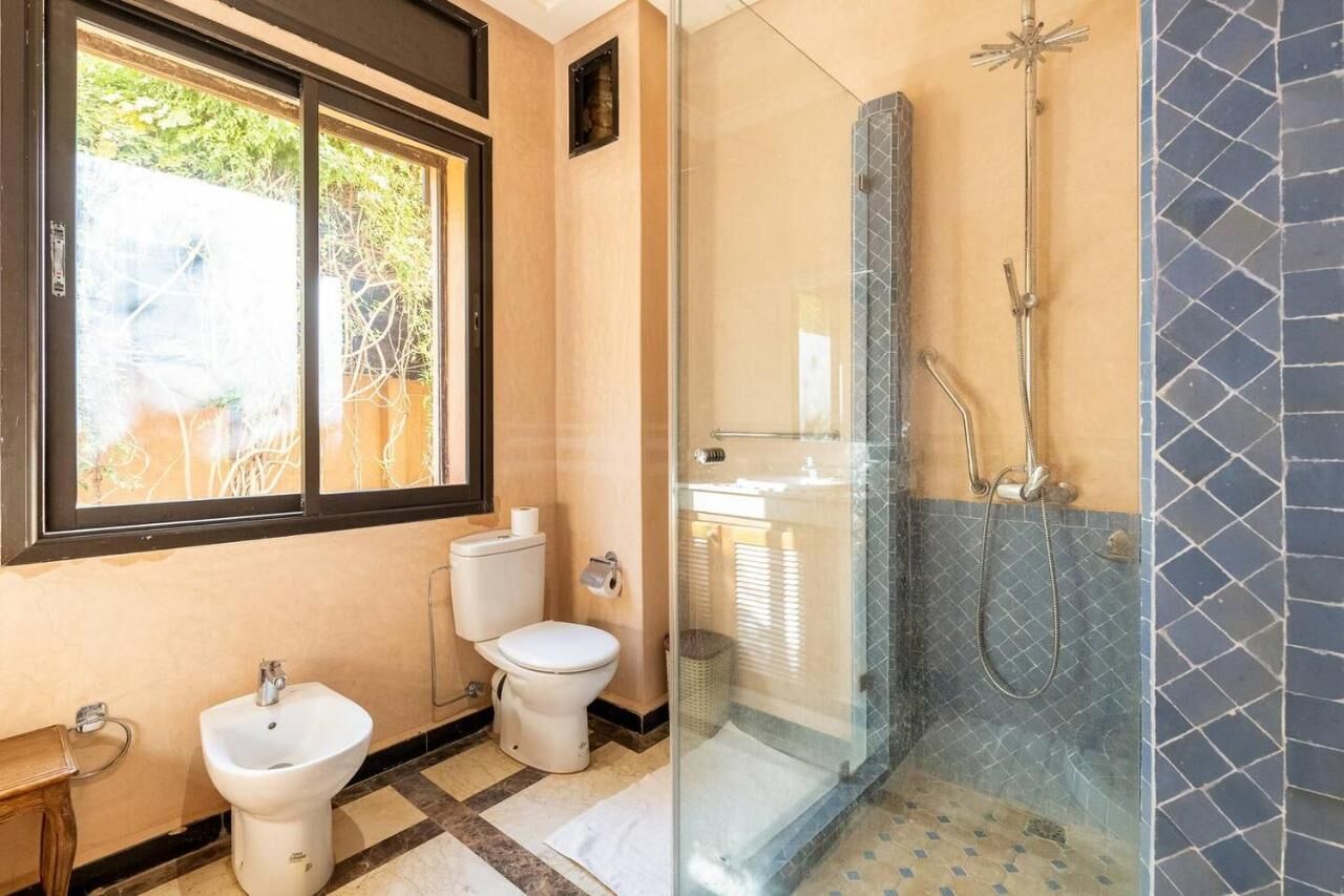 A bathroom with a toilet, bidet, and glass-enclosed shower.