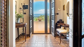 Un couloir menant à un balcon d’où l’on peut admirer la mer, ainsi qu’un piano et un fauteuil.