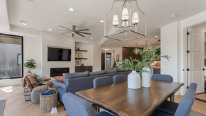 A modern living room with a large sectional sofa, a dining table, and a ceiling fan. - The Yucca Flower #11: Dog Friendly + Luxury Home (Ivins)