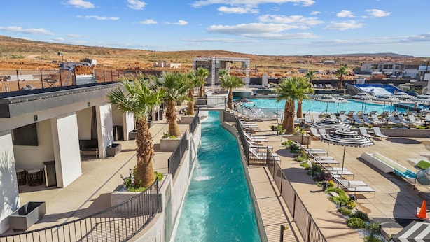 Un área de piscina con tobogán de agua, sillas de descanso y palmeras.