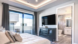 Un dormitorio moderno con una cama grande, un aparador, un televisor de pantalla plana y un baño con bañera.