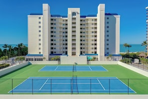 Una cancha de tenis con un edificio al fondo.