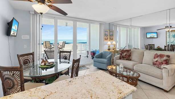 A spacious living room with a large glass table, a sofa, and a ceiling fan.