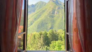 A window with open curtains, offering a view of green mountains and forested areas. - Villa Vico - Private Villa with View, Garden, Pool and Jacuzzi (Vico Pancellorum)