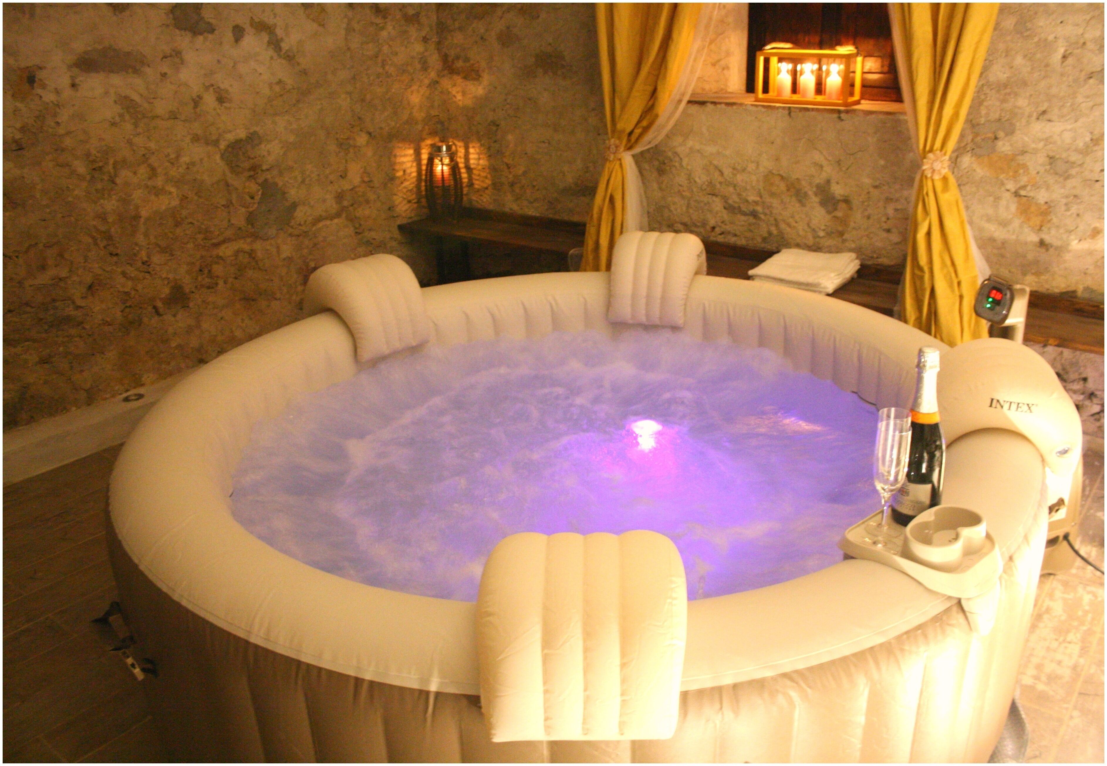 Un bain à remous équipé d’un fauteuil massant, une bouteille de champagne et une télécommande.