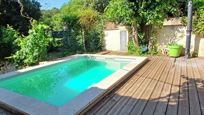 Une piscine rectangulaire entourée d’une terrasse en bois.