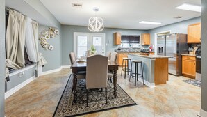 Una cocina moderna con una isla central, armarios de madera y un refrigerador de acero inoxidable.