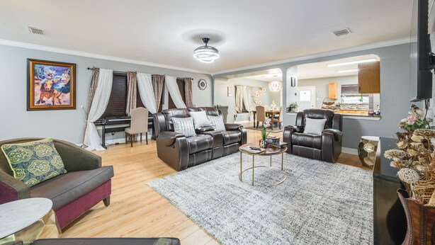Una sala de estar con un piano, sofás de cuero, una mesa de centro y un área de comedor al fondo.