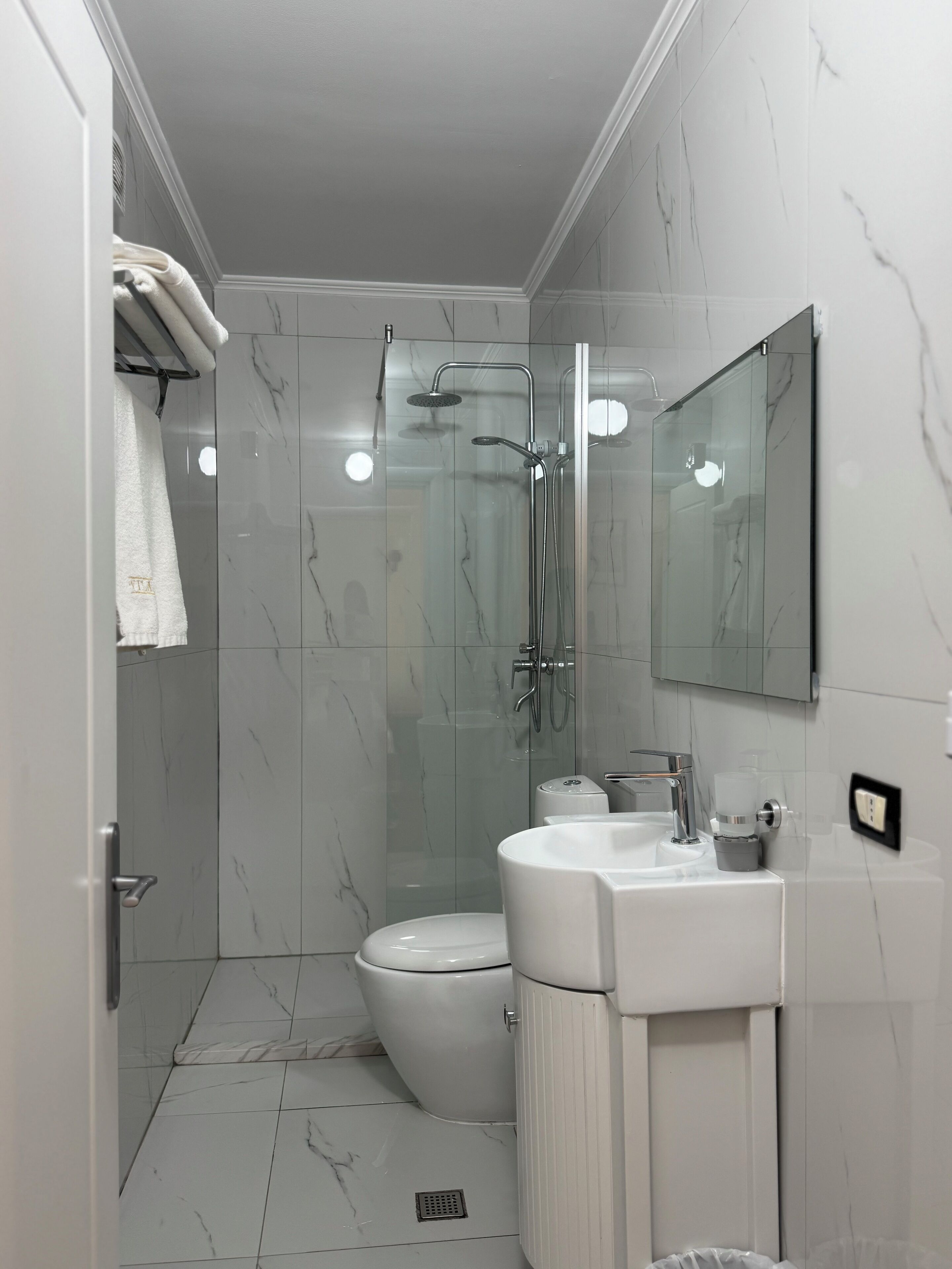 A modern bathroom with a glass-enclosed shower, a toilet, and a sink with a mirror above it.