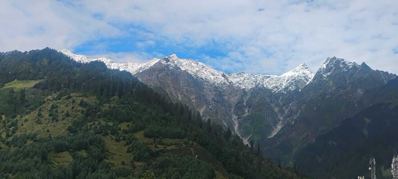 A mountainous landscape with snow-capped peaks and dense forested areas.