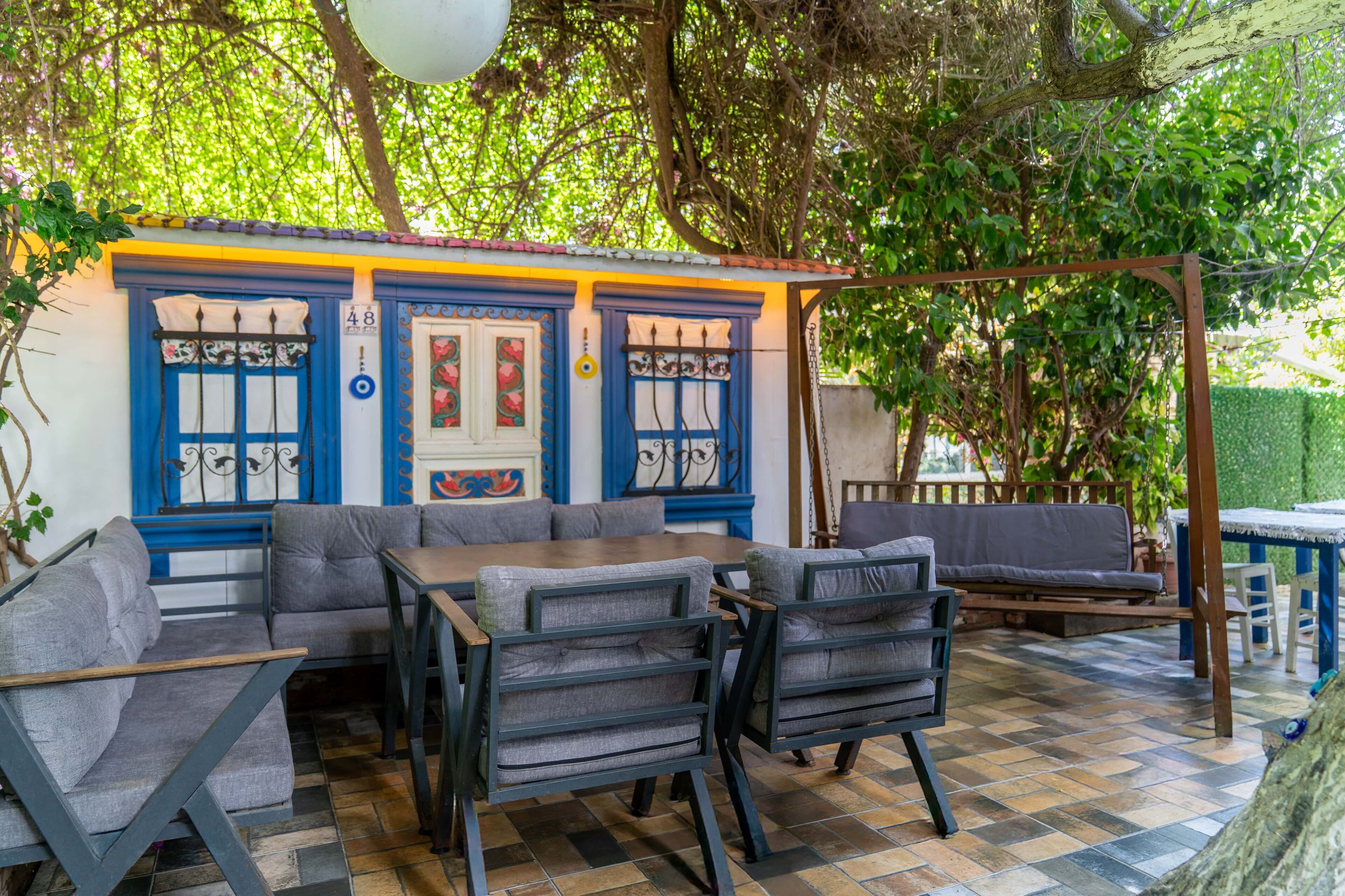 An outdoor seating area with a checkered floor, blue and yellow walls, and a wooden swing.