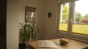 Una cocina con una mesa de madera, una planta en maceta, un cuenco de fruta y un menú sobre la mesa.