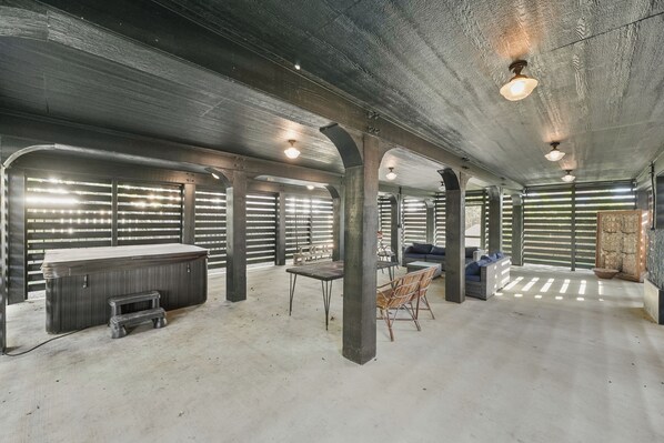 A spacious room with a large wooden table, a bench, and a sofa. There are multiple columns supporting the ceiling, and the room has a rustic, industrial feel.