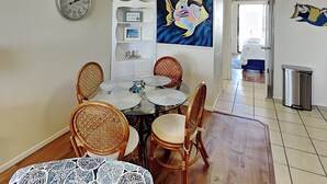 Un coin repas avec une table ronde, des chaises en osier et une horloge au mur.