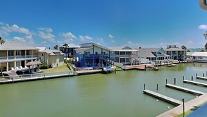 Un port de plaisance avec des bateaux amarrés, une piscine et un bâtiment à la façade bleue.