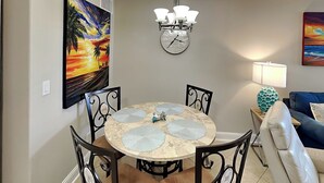 Un espace repas comprenant une table ronde, des chaises, une horloge murale et des œuvres d’art.