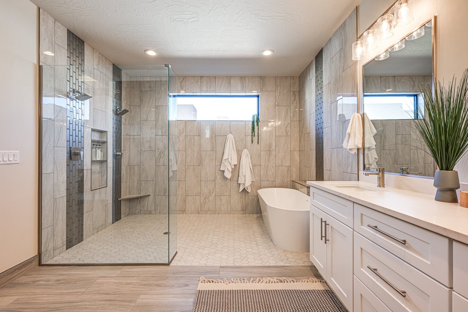 Une salle de bain moderne dotée d’une douche à parois de verre, d’une baignoire sur pieds et d’un meuble-lavabo avec un grand miroir.