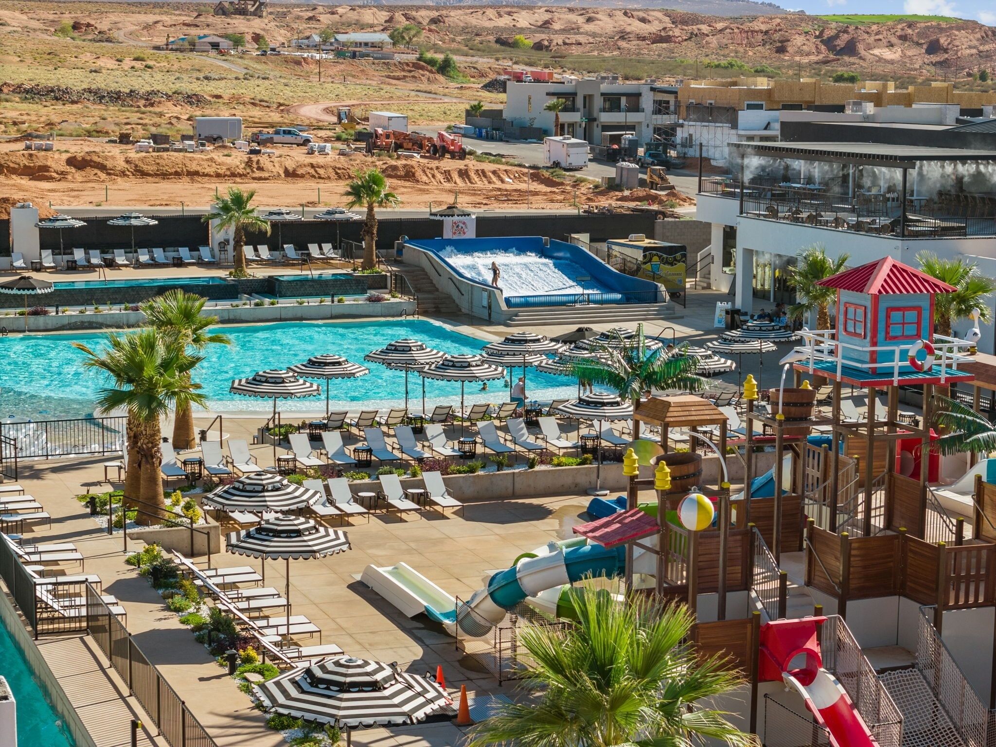 Ett semesterhotell med en stor pool, solstolar, parasoller och en vattenrutschkana.