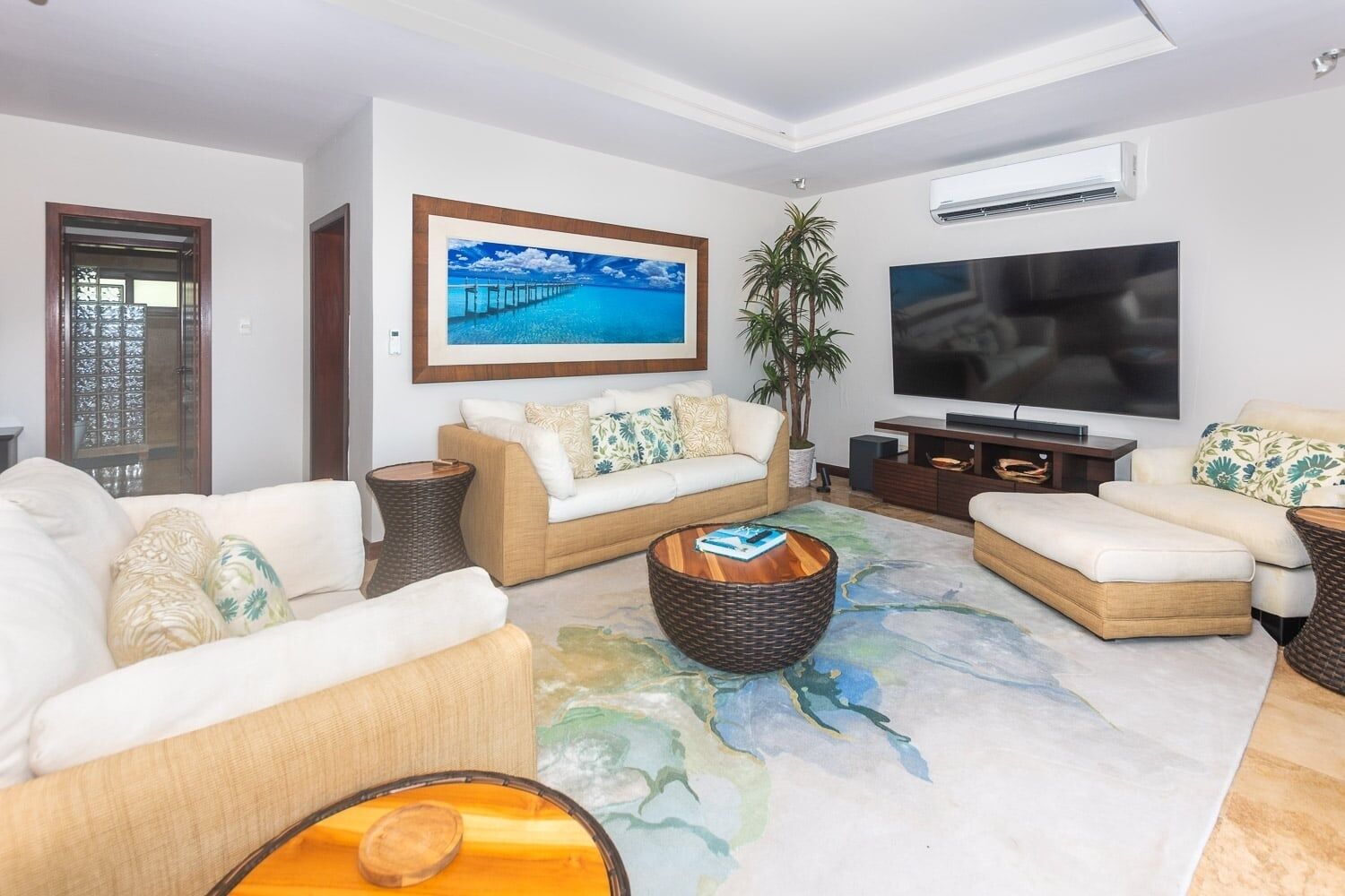 A living room with a sofa, a coffee table, a TV, and a painting on the wall.