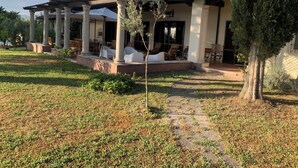 A house with a covered patio, outdoor seating, and a garden path. - Villa il Turchetto, country house with swimming pool 2km from Terme di Saturnia (Saturnia)