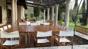 An outdoor patio with a wooden table and chairs, surrounded by columns and a pergola. - Villa il Turchetto, Country House with Pool, 2 km from Terme di Saturnia (Saturnia)