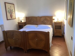 A wooden bed with a headboard, two bedside tables with lamps, a nightstand, and a wall-mounted shelf. - Villa il Turchetto, Country House with Pool, 2 km from Terme di Saturnia (Saturnia)
