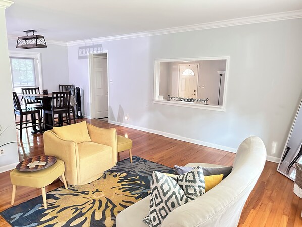 A living room with a sofa, armchair, and a dining area with chairs and a table.