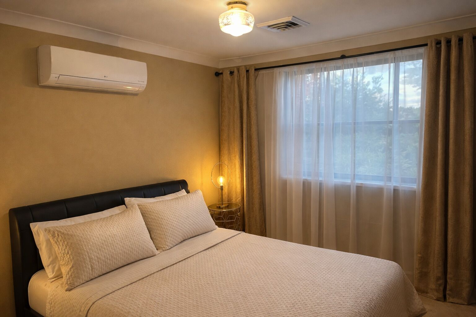 Una habitación de hotel con una cama, aire acondicionado, una lámpara de noche y una ventana con cortinas.