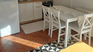 Une cuisine compacte avec des meubles blancs, une cuisinière, un évier et une table à manger avec des chaises.