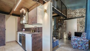 A modern kitchen with a built-in dishwasher, a stainless steel range hood, and a stone wall in the background.