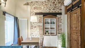 Un'accogliente sala da pranzo caratterizzata da una parete in pietra, un mobiletto in legno e un tavolo con sedie.