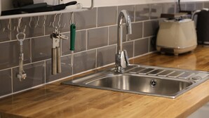 Eine Küche mit Spüle aus Edelstahl, einer Holzaarbeitsplatte und einem modernen Wasserhahn.
