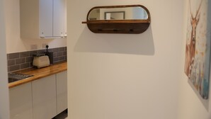 Eine Küche mit weißen Schränken, einer Holzausziehtischplatte, einem Toaster und einem an der Wand befestigten Spiegel.