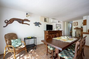 Ein Essbereich mit Holztisch, Stühlen, einem Fernseher und Wandbildern.
