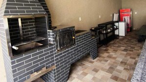 A kitchen with a brick oven, a dining table, and a red cabinet.