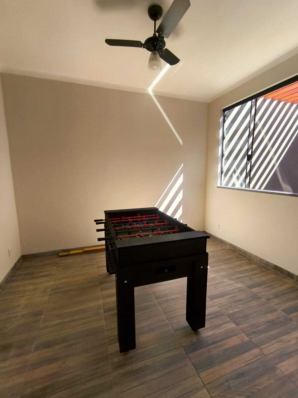 Ein Zimmer mit Kicker, Deckenventilator und einem Fenster mit Jalousien.