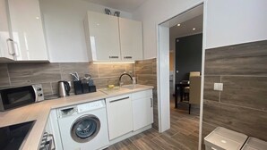 A modern kitchen with white cabinets, a washing machine, and a microwave.