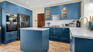 A modern kitchen with blue cabinetry, a central island, and stainless steel appliances. - Historic House in Bourton on the Water (Bourton-on-the-Water)