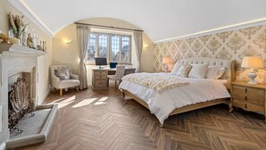 A bedroom with a large bed, a desk, and a fireplace. - Historic House in Bourton on the Water (Bourton-on-the-Water)