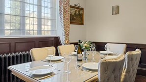 A dining room with a table set for four, a bottle of Gavi wine, and a vase of flowers. - Historic House in Bourton on the Water (Bourton-on-the-Water)