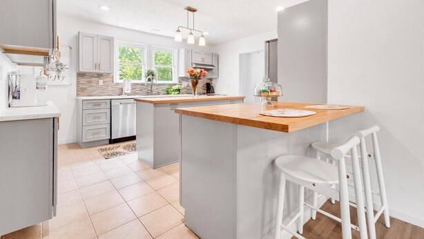 A modern kitchen with white cabinetry, a central island, and bar stools. - Charming Downtown Harrison Home (Harrison)