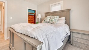 A bedroom with a bed, bedside tables, a nightstand, a lamp, and a window with blinds. - Charming Downtown Harrison Home (Harrison)