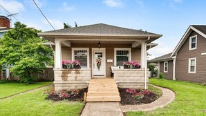 A two-story house with a front porch, a number '614' on the door, and a small garden with pink flowers. - Charming Downtown Harrison Home (Harrison)