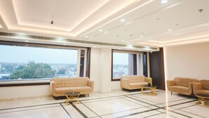 A spacious, modern living room with large windows, two sofas, and a coffee table. - Hotel Raghukul Grand (Azamgarh)