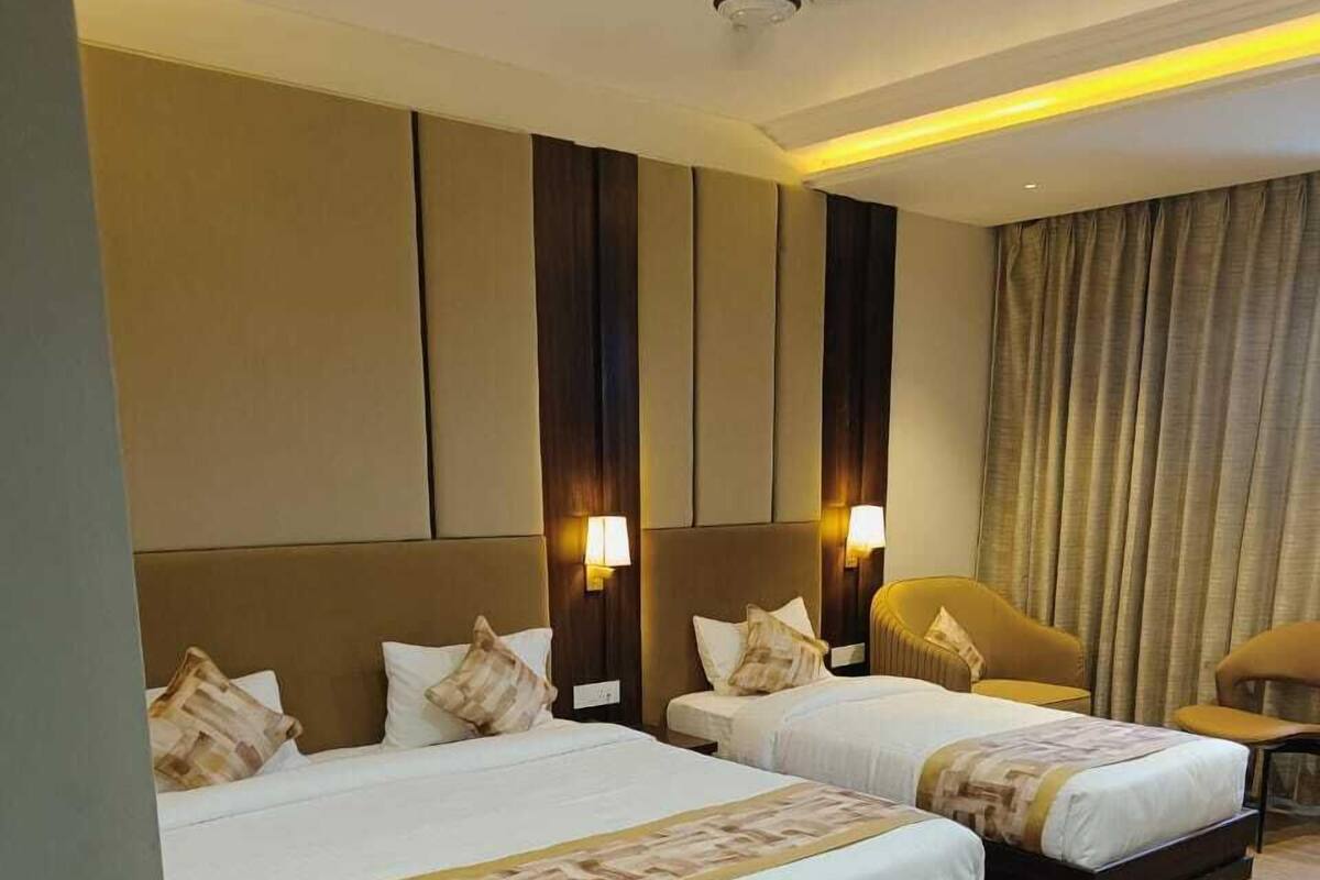 A hotel room with two beds, a ceiling fan, and a large window with curtains.
